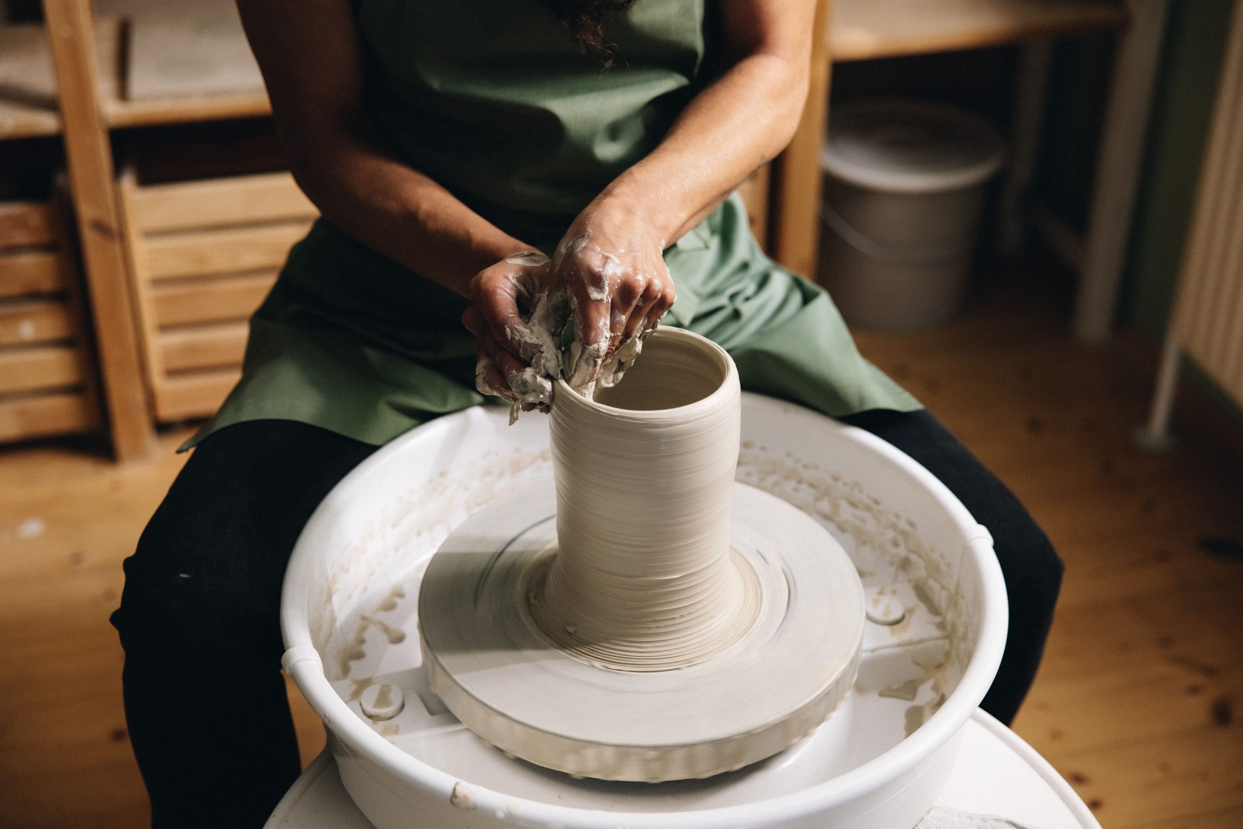 Intensivkurs Töpfern auf der Scheibe in Wien - Hände formen Ton auf der Töpferscheibe im Verenics Studio.