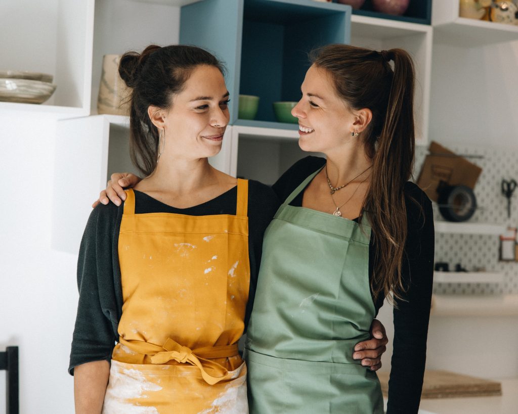 Verena und Valentina, Schwestern und Business-Partnerinnen, im Töpferstudio Arm in Arm - Verbundenheit und Kreativität.